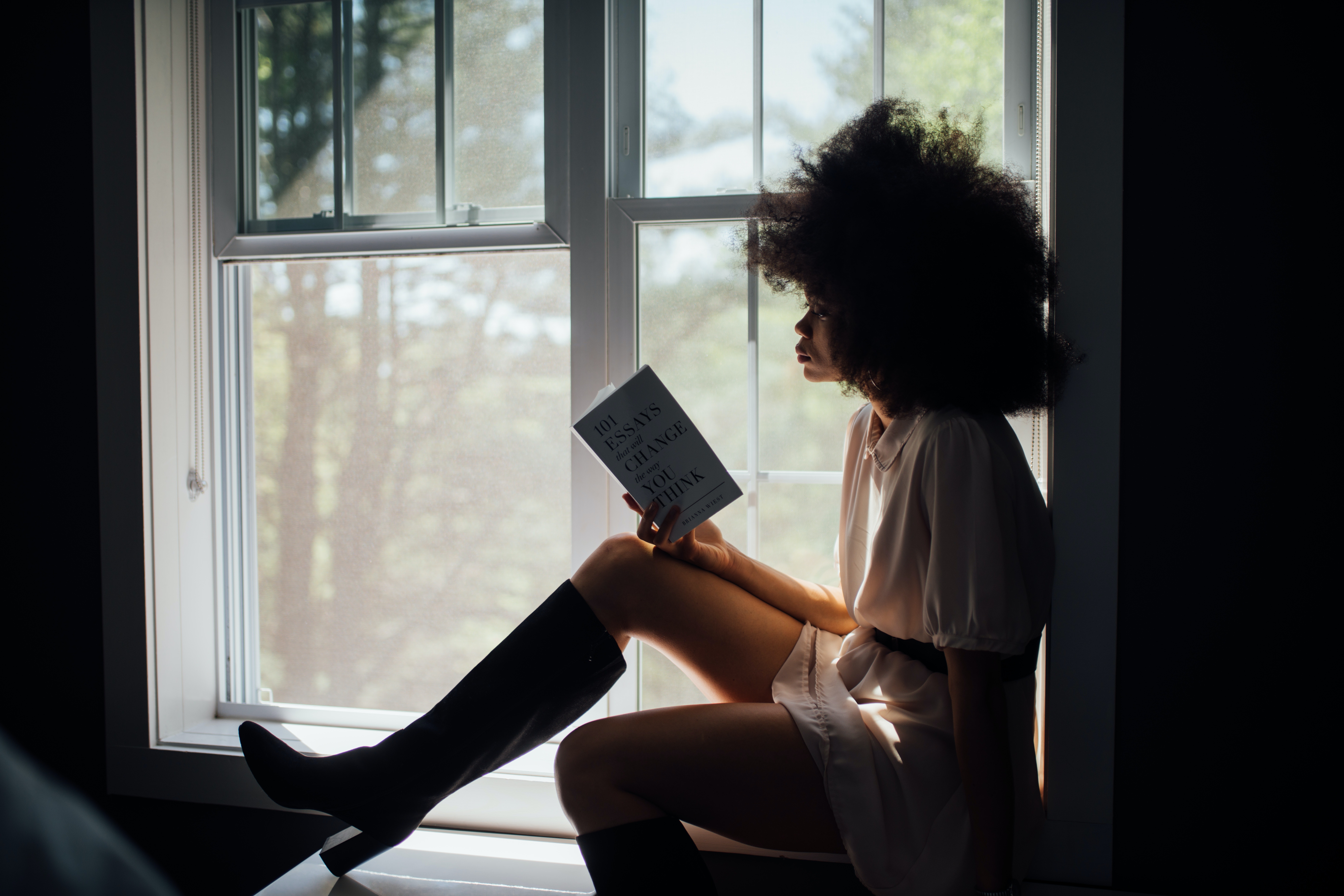 Vrouw zit op vensterbank te lezen en is eenzaam