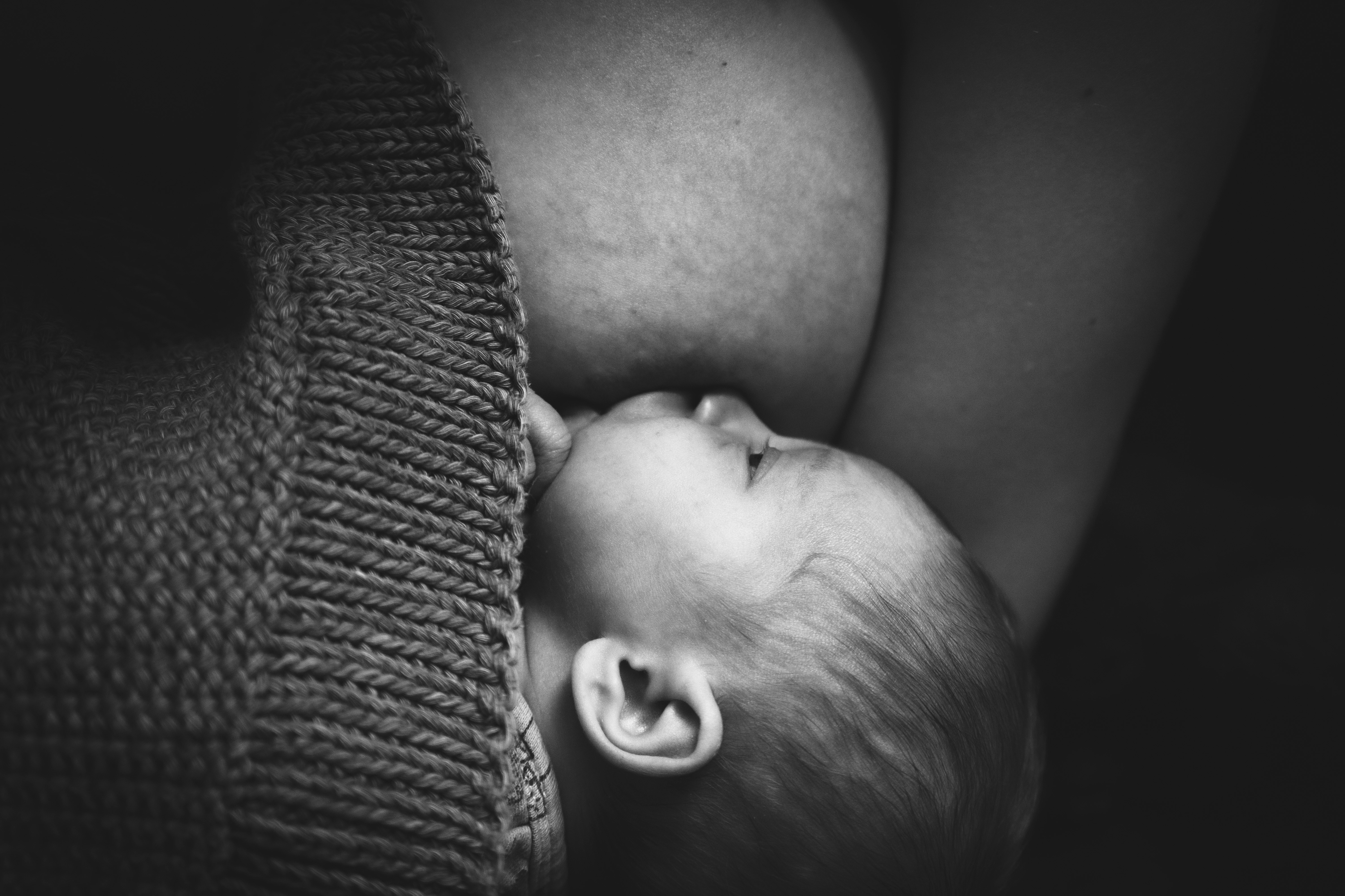 Zwart wit foto van baby die borstvoeding krijgt, waarschijnlijk nachtvoeding