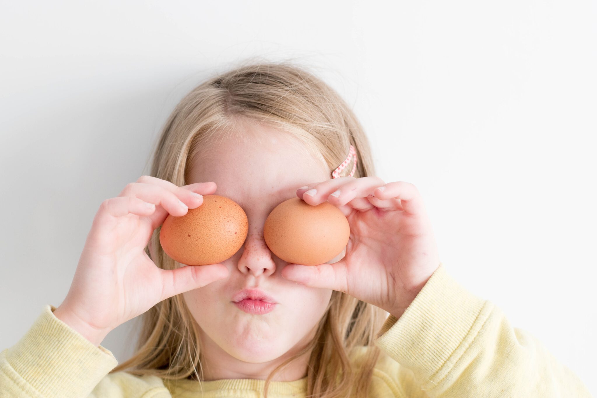 Meisje met eieren voor haar ogen die ze samen met haar ouders tot gezonde snacks maakt voor Pasen