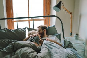 vrouw die met haar man in bed ligt en minder zin heeft in seks tijdens haar zwangerschap omdat het anders voelt