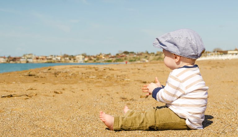Een jongetje op het strand in de stijl van Peaky Blinders met een geweldige babynaam