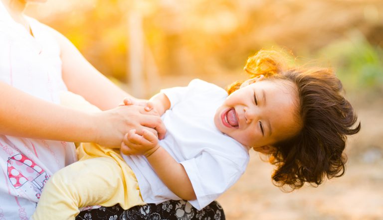 Gevoelig kind dat gekieteld wordt door moeder