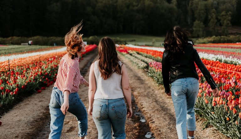 Drie zusjes die door een tulpenveld rennen, waarbij het middelste kind achterblijft