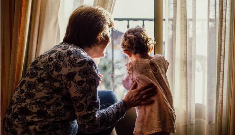 opvoeding / oma staat met kleindochter voor het raam