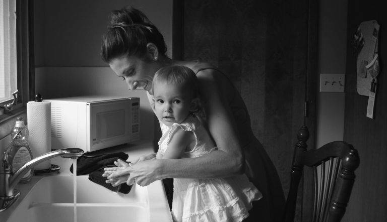Thuisblijfmoeder die de handen van haar dochtertje wast