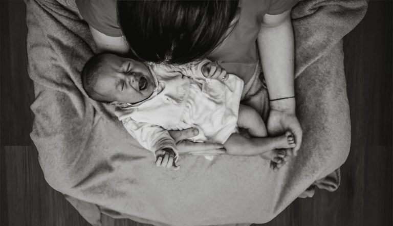 baby huilt na voeding Moeder met huilende baby op haar schoot