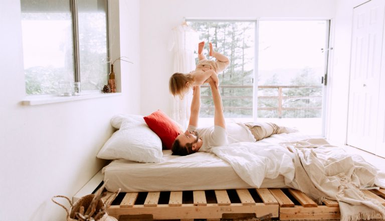 middagslaapje peuter / vader speelt met kind op bed