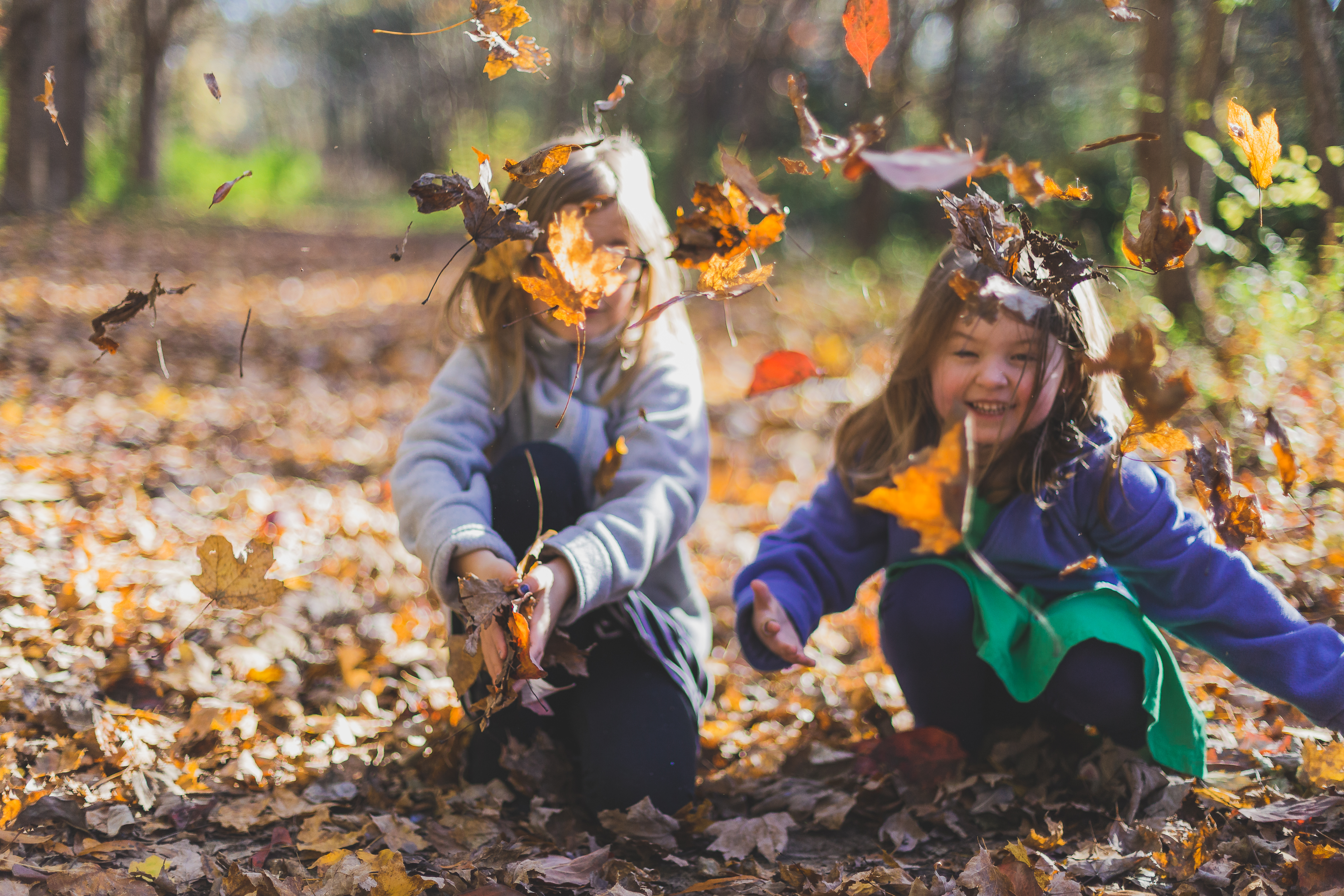 Twee kinderen die uiten in de natuur met blaadjes aan het spelen zijn
