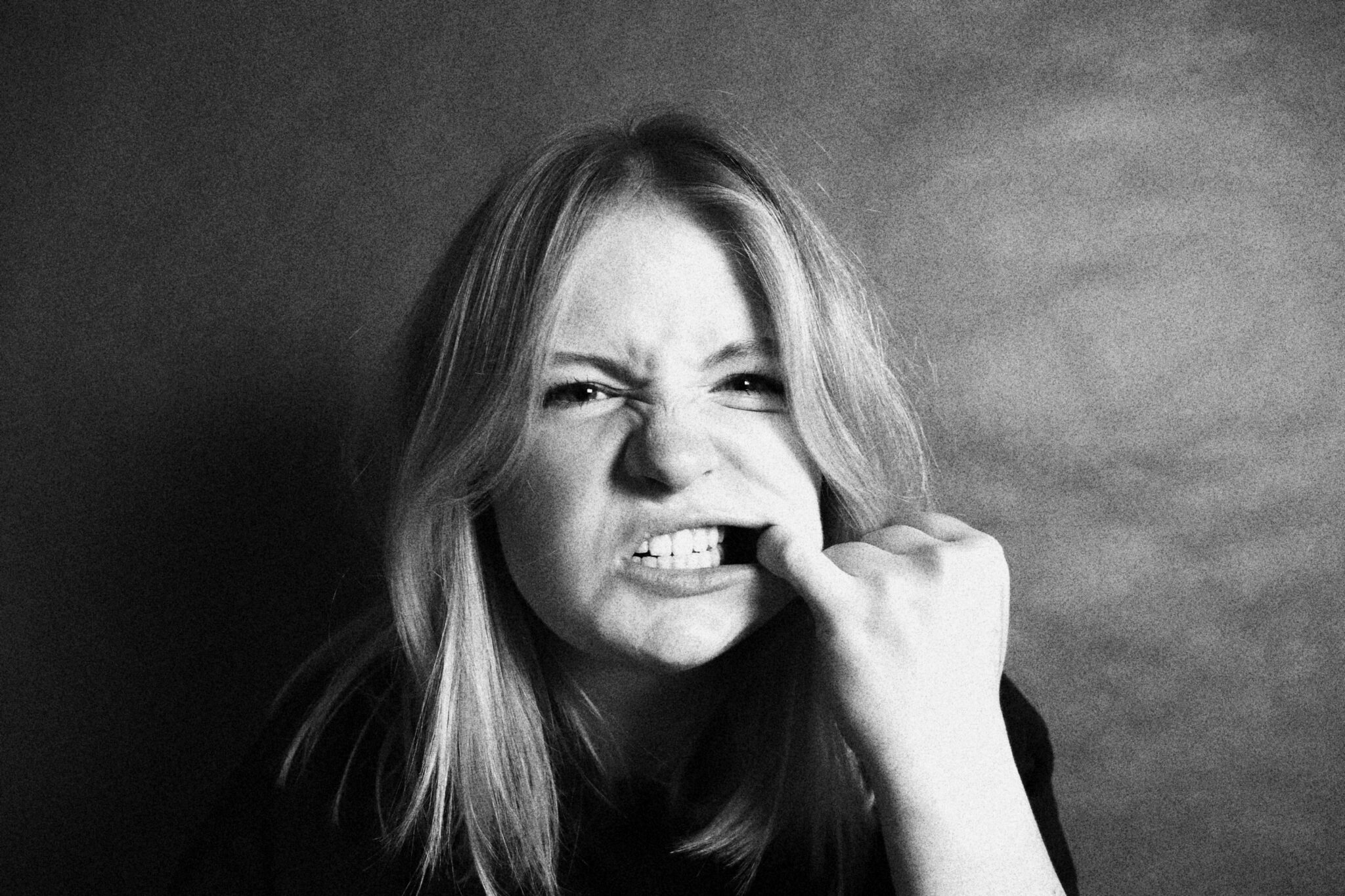 Vrouw die met haar vinger haar stroeve tanden probeert schoon te maken na het eten van spinazie