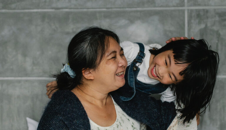 Oma en kleindochter lachend en knuffelend