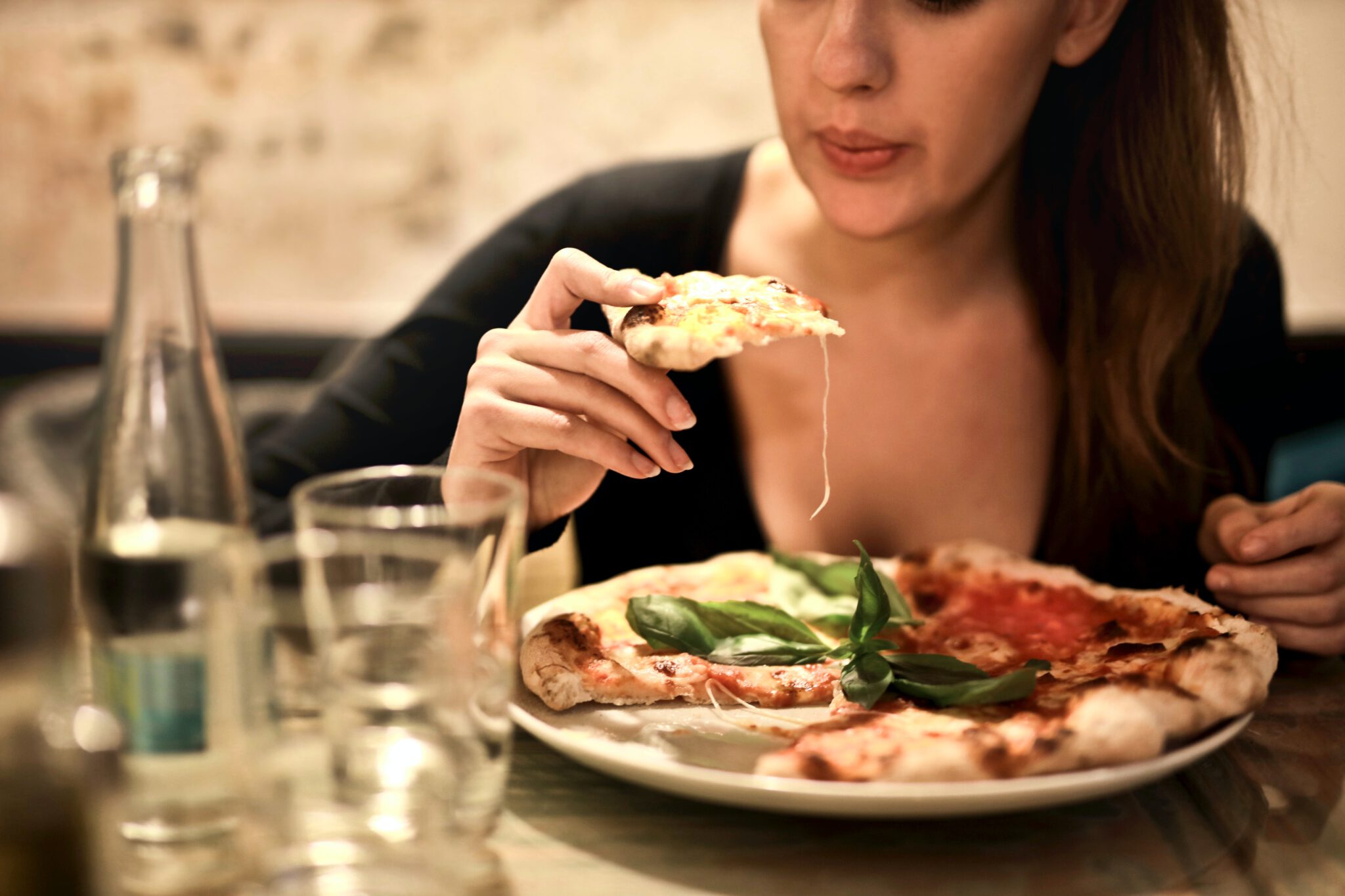 Vrouw die een pizza eet met gesmolten kaas
