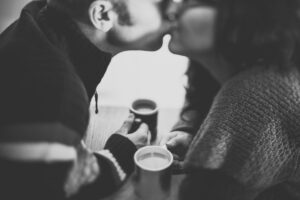 relatie / koppel drinkt koffie en kust elkaar