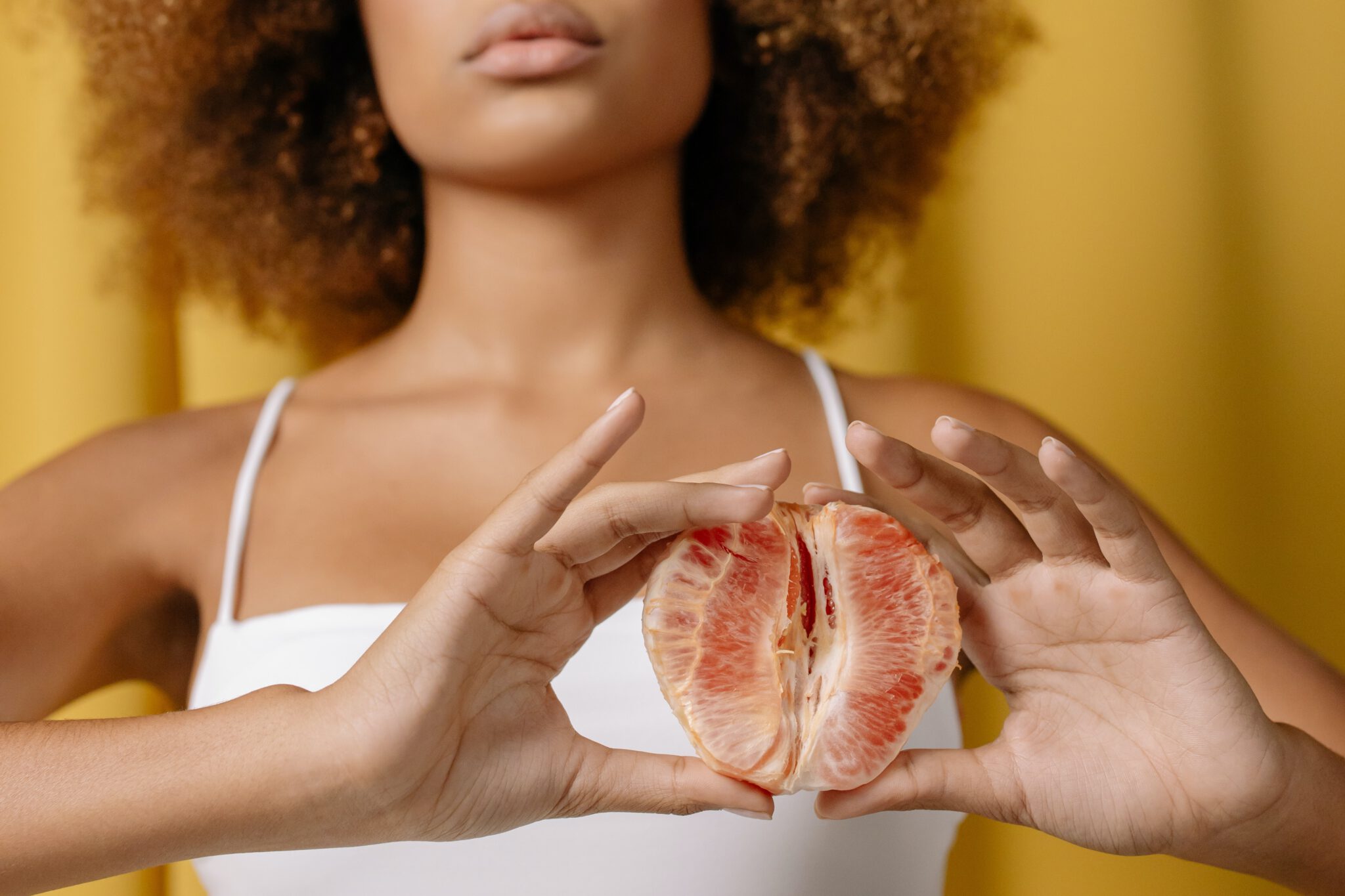 Vrouw die een grapefruit vasthoudt wat symbool staat voor vaginale problememen