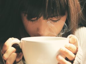 Vrouw die aan een kop koffie ruikt en wil afvallen