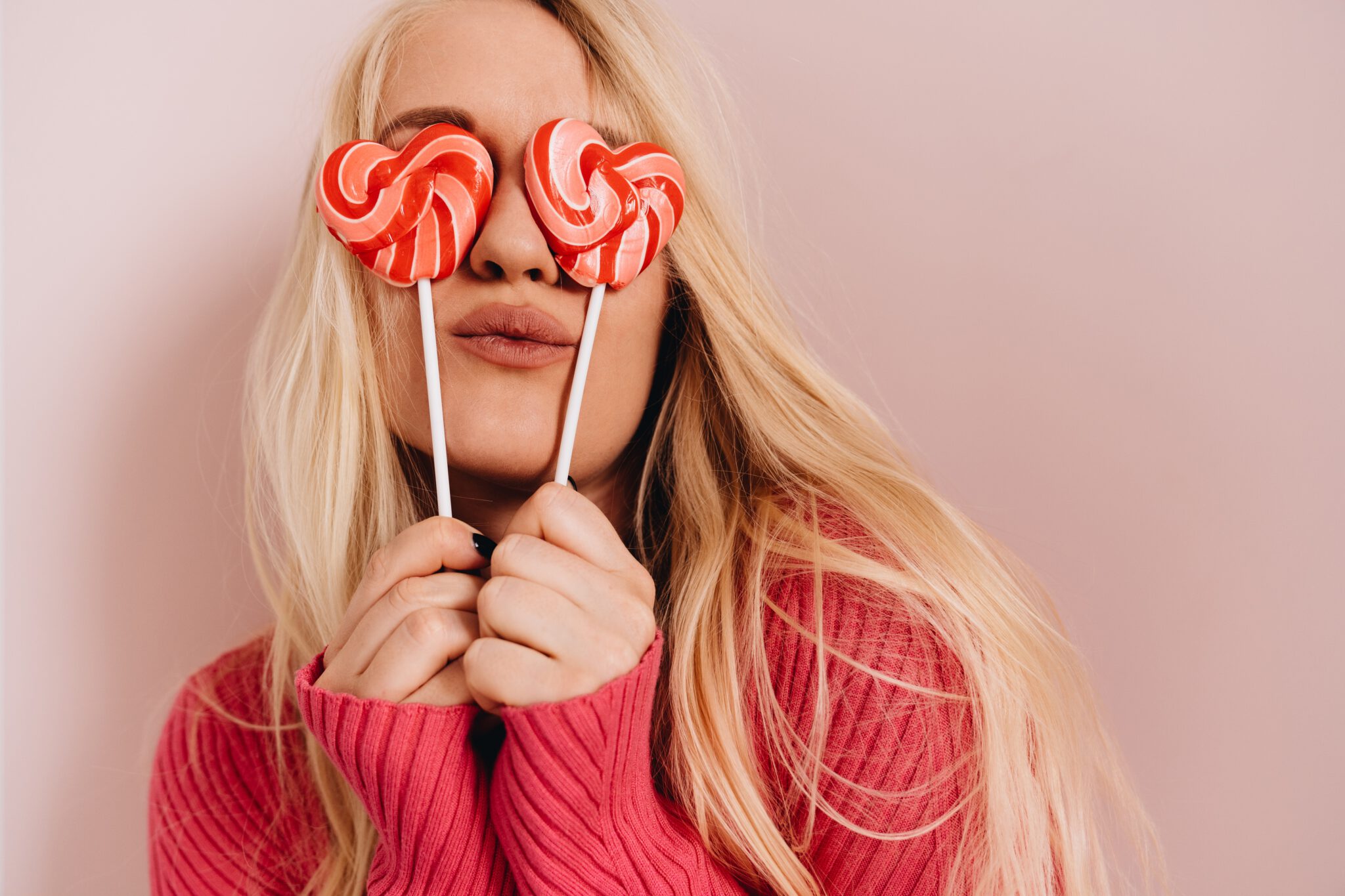 Vrouw die twee hartjes lolly's voor haar ogen houdt omdat die haar als Valentijnscadeau zijn gegeven