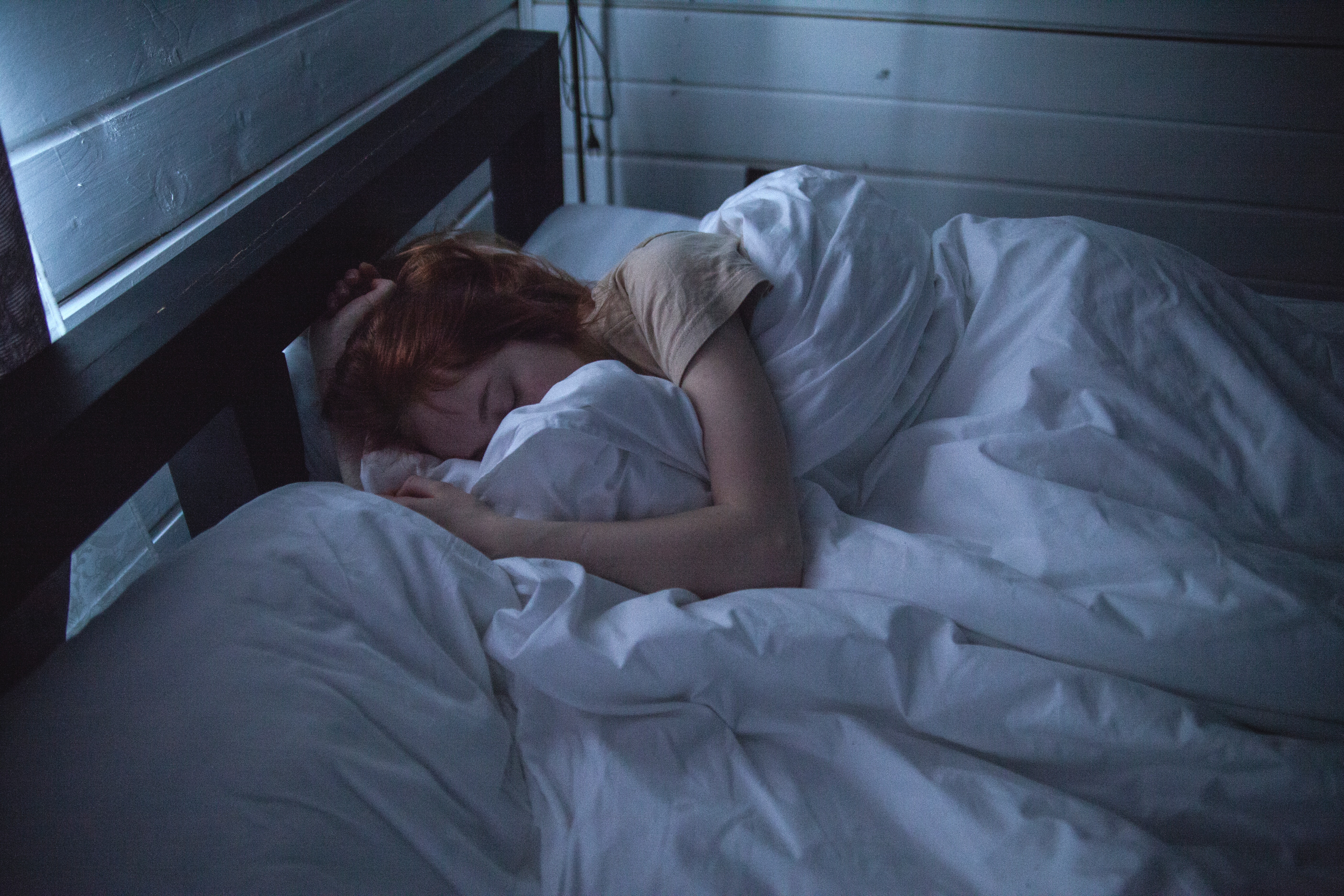 Vrouw die in bed ligt omdat ze last heeft van PMS klachten vlak voor haar menstruatie weer begint