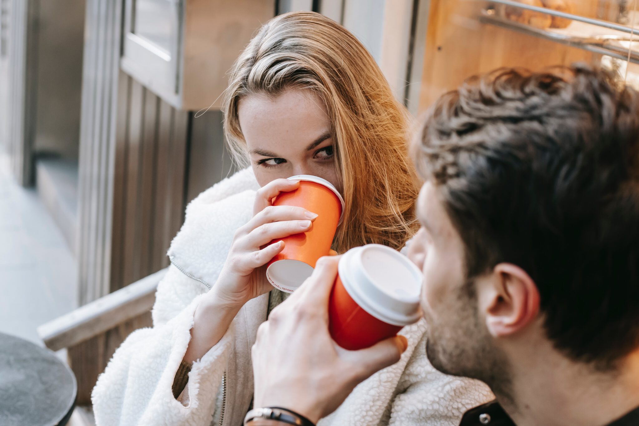 Vrouw die de man aankijkt tijdens hun date terwijl ze koffie drinkt, omdat ze benieuwd is wat de man het eerst aan haar opvalt