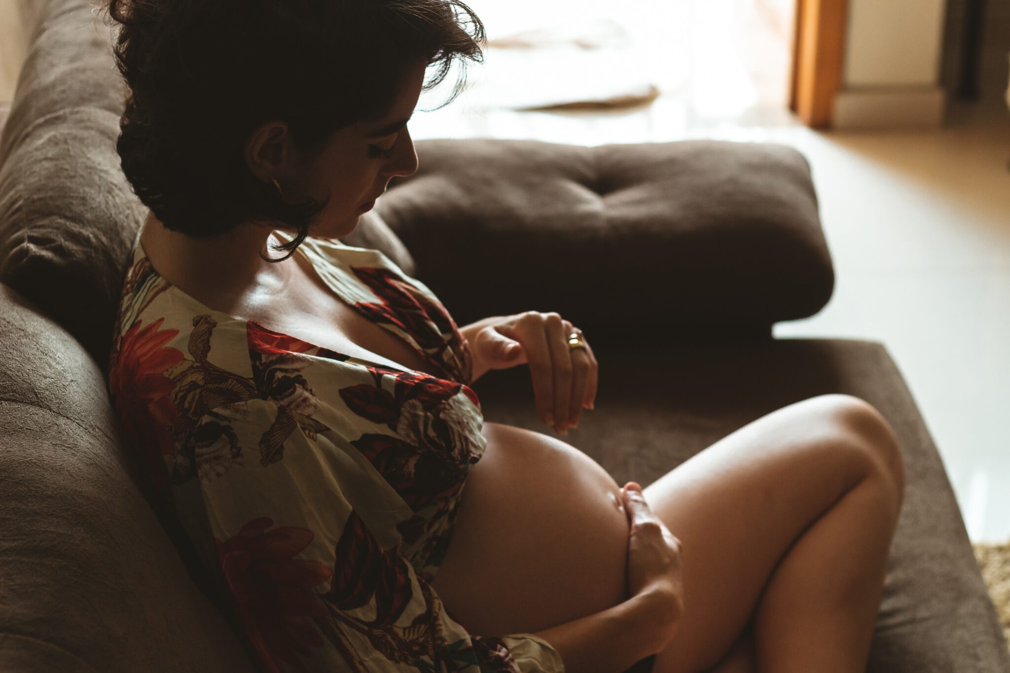 Vrouw die op de bank zit en zichzelf een zwangerschapsmassage geeft