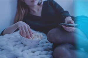 eten / vrouw eet popcorn terwijl ze tv kijkt