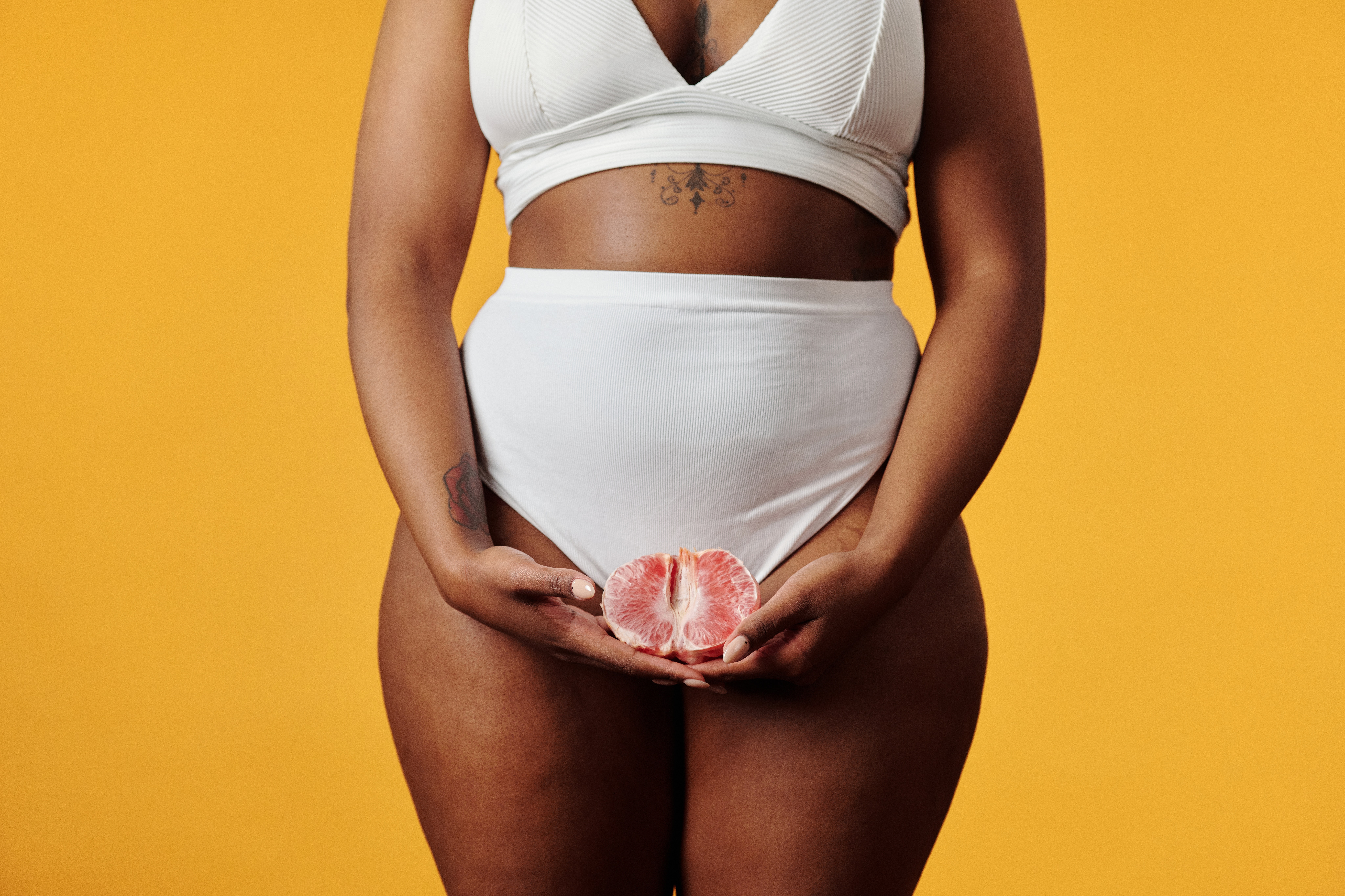 Vrouw die met een grapefruit voor haar kruis staat en onregelmatig ongesteld is
