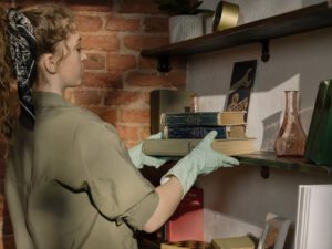 voorjaarsschoonmaak / vrouw maakt boekenplank schoon