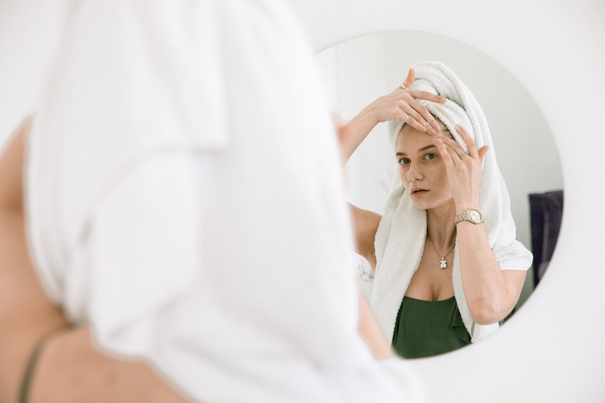 vrouw kijkt in de spiegel naar haar onzuivere huid