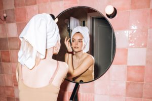 vrouw verzorgt haar huid volgens haar skincare routine in de spiegel