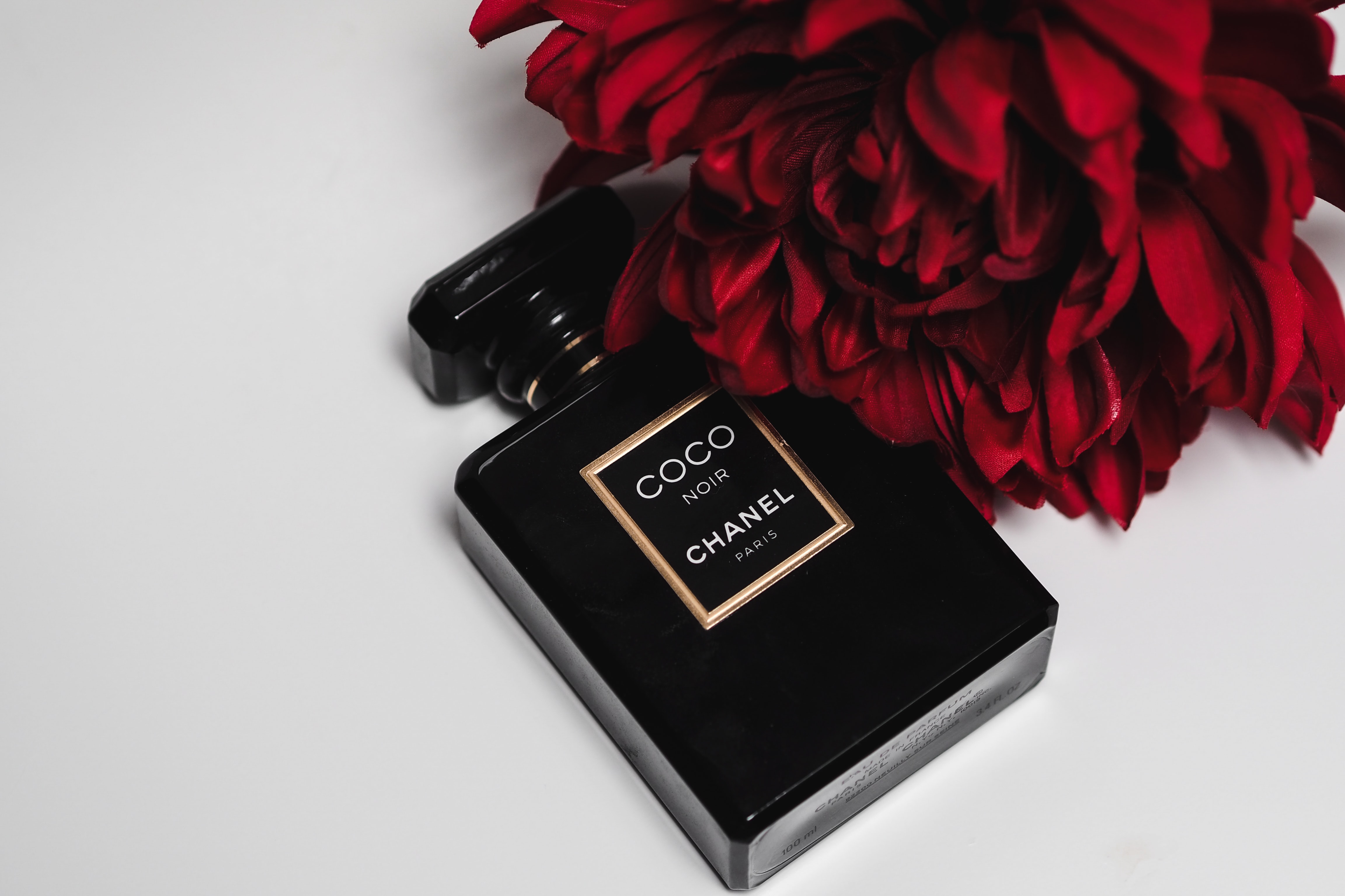 Zwart parfumflesje Coco Chanel met rode roos. Lessen van coco chanel