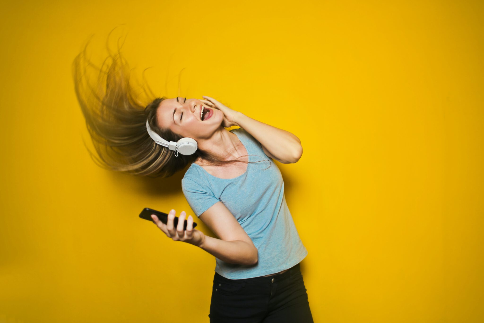Vrouw met headphone zingt vrolijk mee met muziek voor het schoonmaken