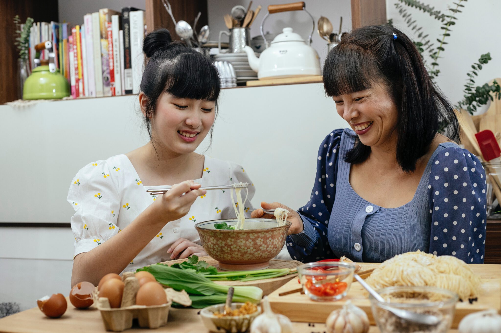 Twee Aziatische vrouwen eten soep met stokjes. Soep voor herstellen postpartum lichaam