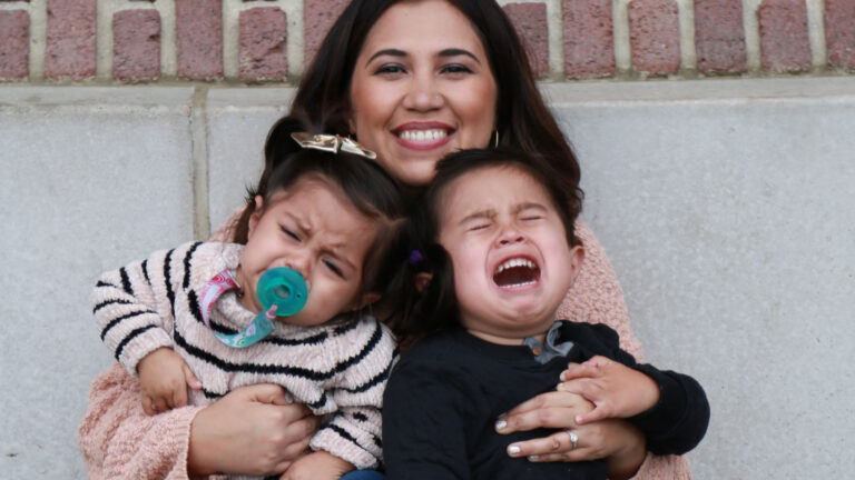 vrouw houdt kinderen vast maar kinderen willen niet meewerken
