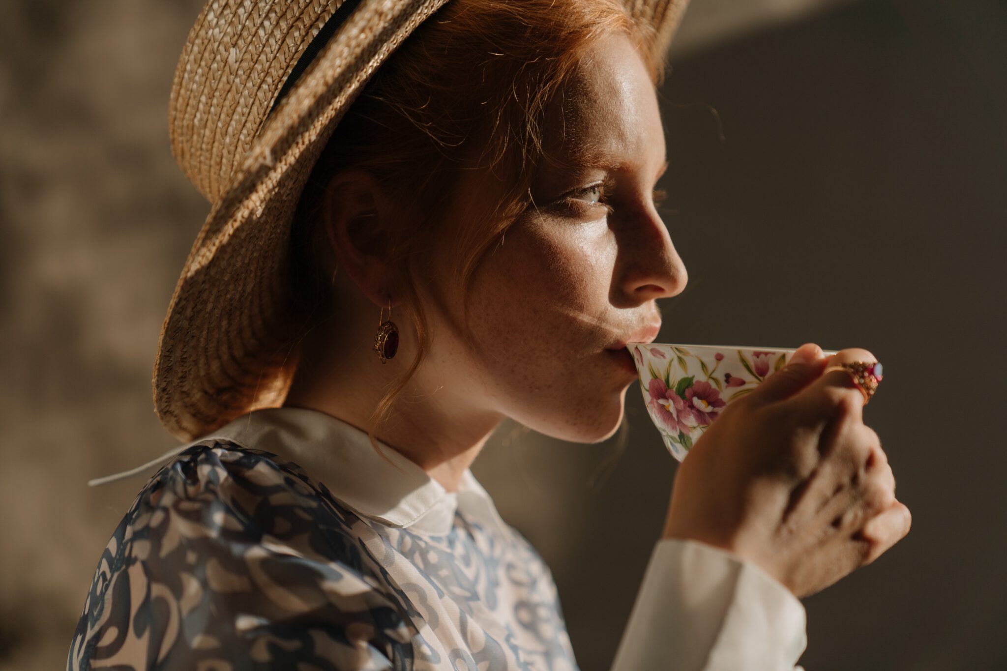 Vrouw neemt slokje uit theekopje en zit in de zon terwijl haar huid vitamine d krijgt