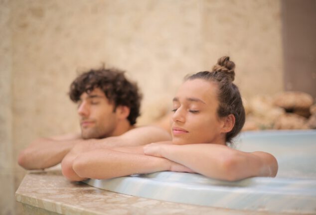 Vrouw en man liggen ontspannen in een hot tub, en doen deze herkenbare dingen in een spa